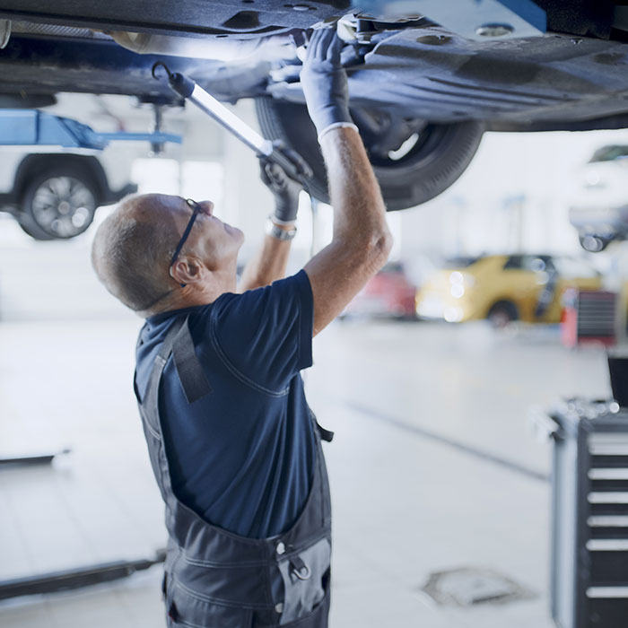 a mechanic inspects a car's underside