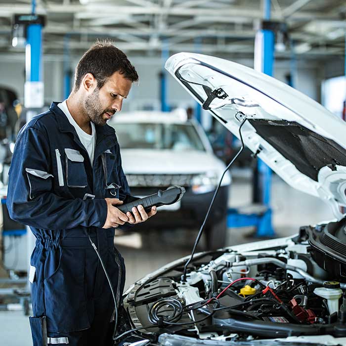 A mechanic in blue coveralls writes on a tablet