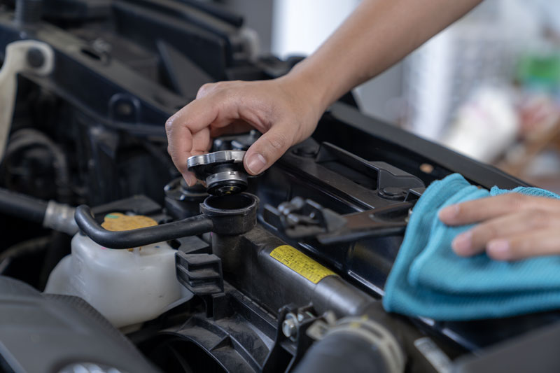 A person is removing a car radiator cap